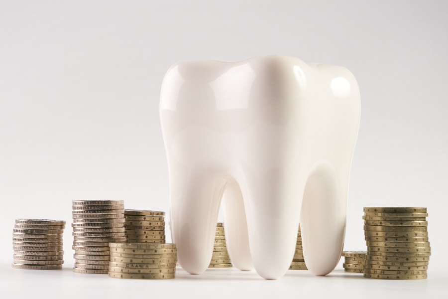 Model of a tooth next to stacks of coins.