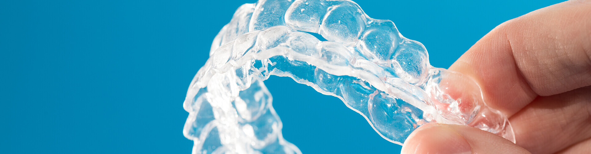 closeup of a person holding a set of Invisalign clear aligners