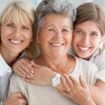 A grandma, mom, and daughter smile together